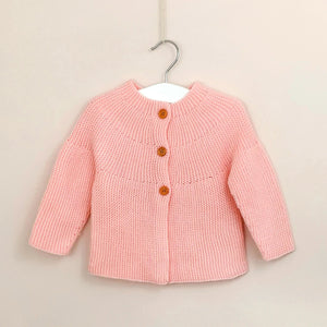 Girls Spanish style knitted cardigan in baby pink, fastened with three wooden buttons.