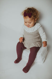 Halle dressed head to toe in Bel Bambini style, wearing our scallop knitted romper in tauper, made with supersoft yarn this has to be one of the prettiest rompers. Teamed with our rib knitted tights, bow headband and lace collar top. 