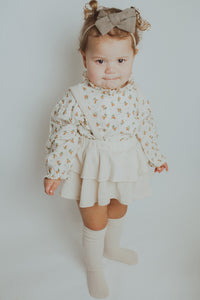 Spring girls outfit in cream, complete with a floral print shirt and frilly bloomers with removable straps. Model shot showing one of our new girls styles.