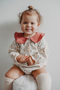 Baby modelling our spting romper in a beautiful floral print with a contrast statement collar.