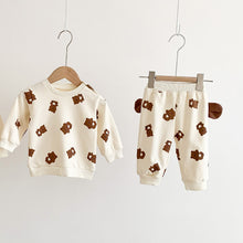 Load image into Gallery viewer, Long sleeved sweater and jogging bottoms for baby girls and baby boys in a teddy bear print. Teddy bear ears feature on each side of the joggers making this lounge set super cute. Exclusive to Bel Bambini baby clothing boutique UK.