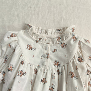 Detail shot of he printed floral romper for girls with gathers, frills and buttons. Shop online today.