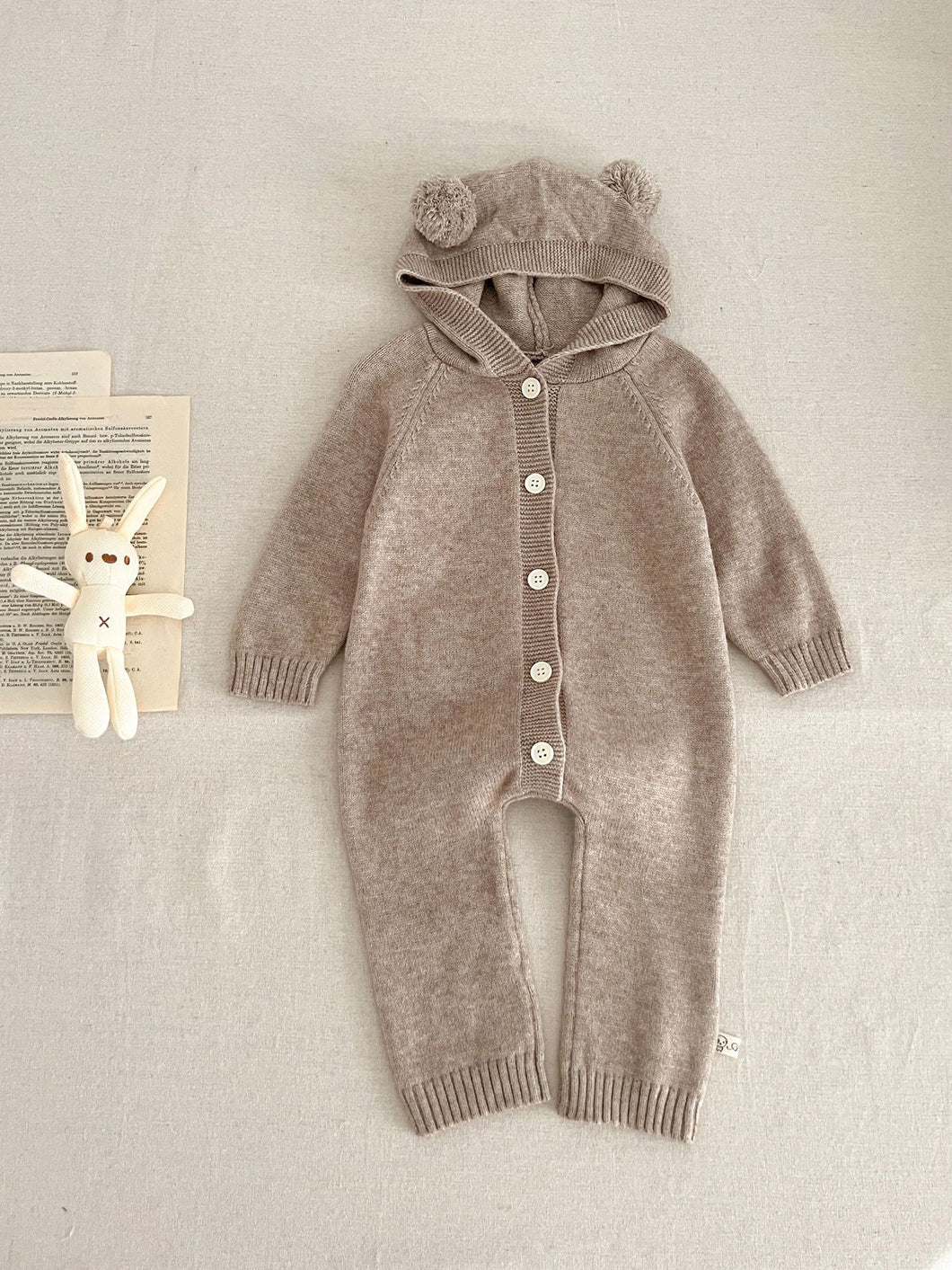 Baby bear knitted romper in taupe. Unisex baby all in one suit made from super soft cotton yarn. Perfect new baby gift. Shop our baby and toddler clothing exclusively at Bel Bambini today.