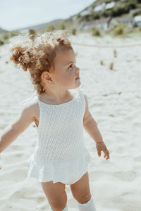 Scallop firll knitted romper. Lightweight and made from a supersoft cotton yarn. Popper fastenings to the crotch and t straps to the shoulders.