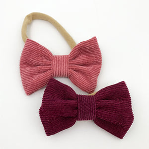 Baby girls bow headbands with a soft and stretchy band. Available in packs of two and a variety of colours. Red and berry headbands for toddler girls and babies. Exclusive to Bel Bambini baby boutique.