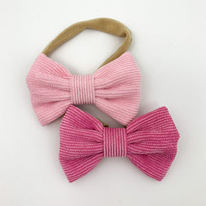 Pink headbands for little girls. A set of two bow headbands in candy pink and fuchsia pink. Corduroy bow with an elasticated headband. Soft and comfortable for you little girls head. Exclusive to Bel Bambini baby boutique.