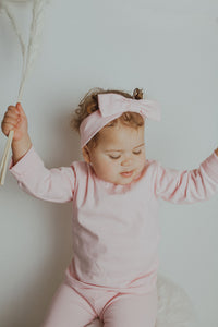 Baby girls loungewear set in baby pink. Set made in supersoft 100% cotton fabric. Headband, long sleeve tee and leggings are all included in this super cute set. Also available in blue.