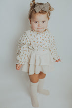 Load image into Gallery viewer, Spring girls outfit in cream, complete with a floral print shirt and frilly bloomers with removable straps. Model shot showing one of our new girls styles.