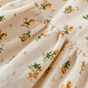 Pretty floral print in orange and green on a soft apricot base.