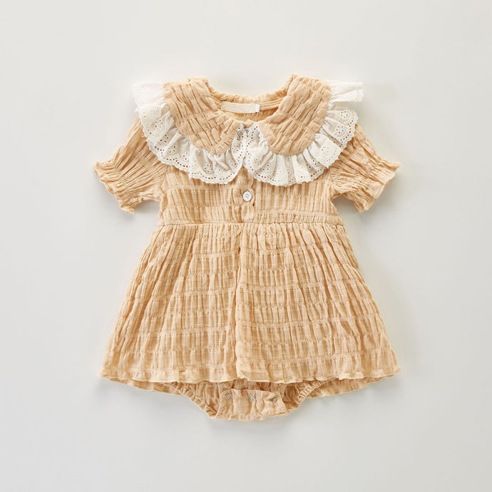 Girls romper dress with short sleeves. Fashionable peter pan collar with a broderie anglaise trime. Timeless romper dress on a textured fabric base in a beautiful vintage apricot  shade. Perfect outfits for girls formal dress. 