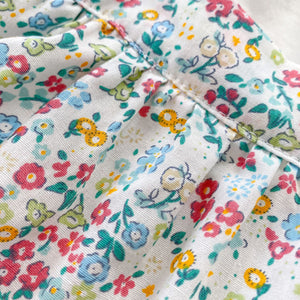 Detail our beautiful flower print in yellows, reds, greens and blues on a white base. Exclusive baby clothing at Bel Bambini baby boutique. UK baby clothes for girls and boys.